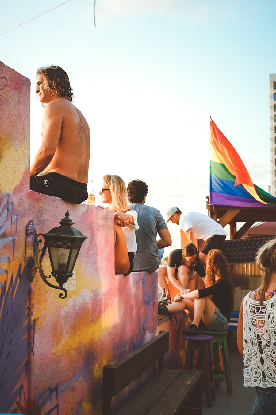 Young person on a rooftop holding a pride flag, representing youth voice and identity in politics
